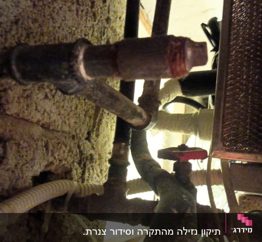 צינורות מתכת וברז אדום במערכת אינסטלציה